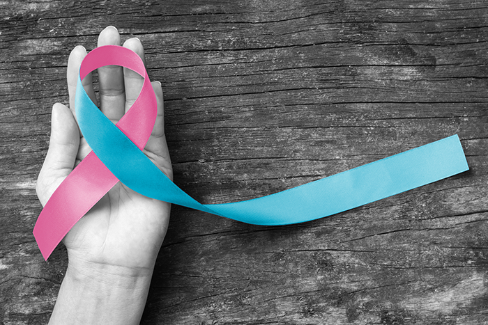 hand holding a pink and blue ribbon