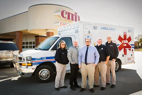 Five people standing in front of an ambulance